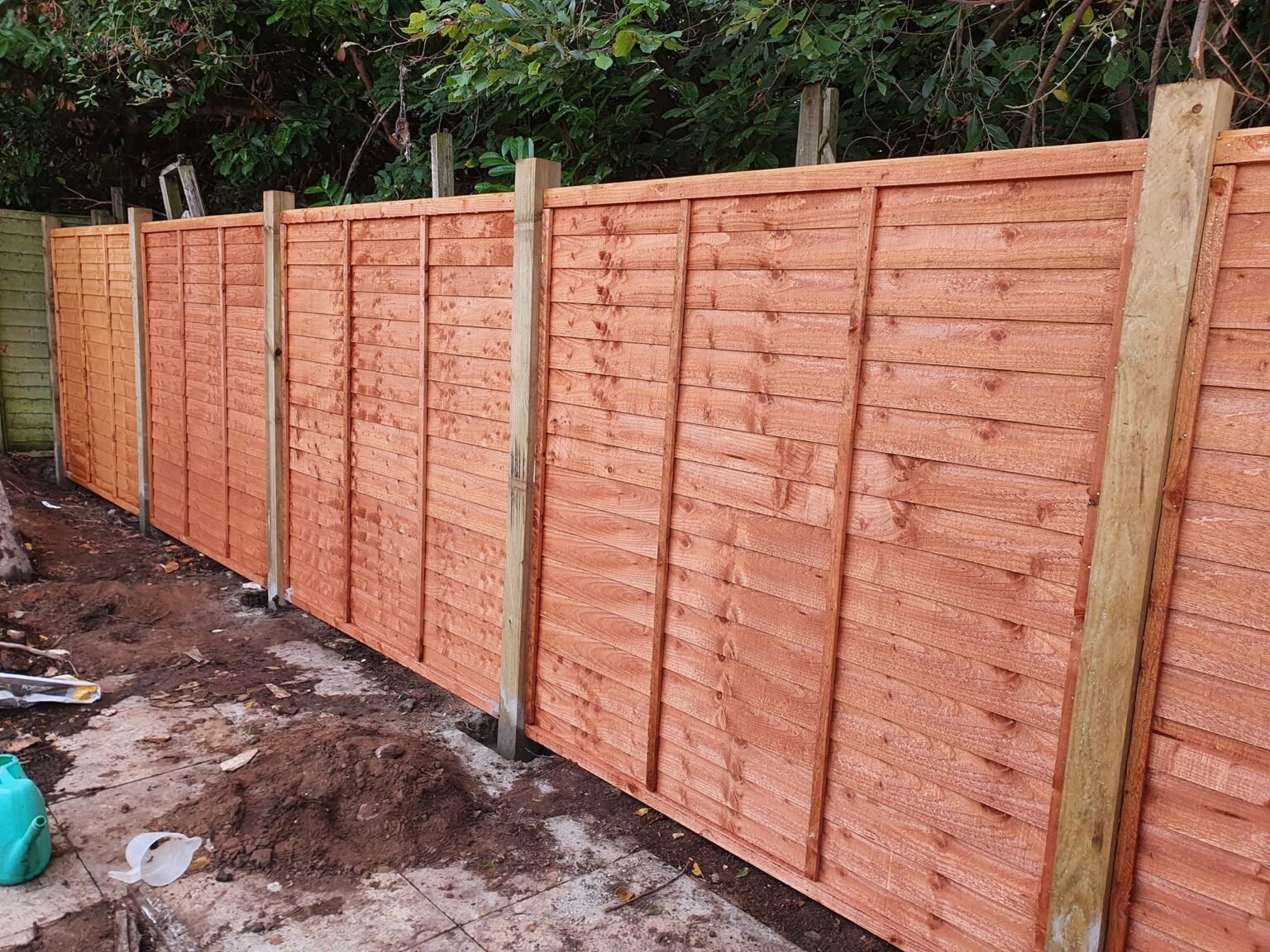 Timber fence panels installed between concrete supporting posts along a boundary