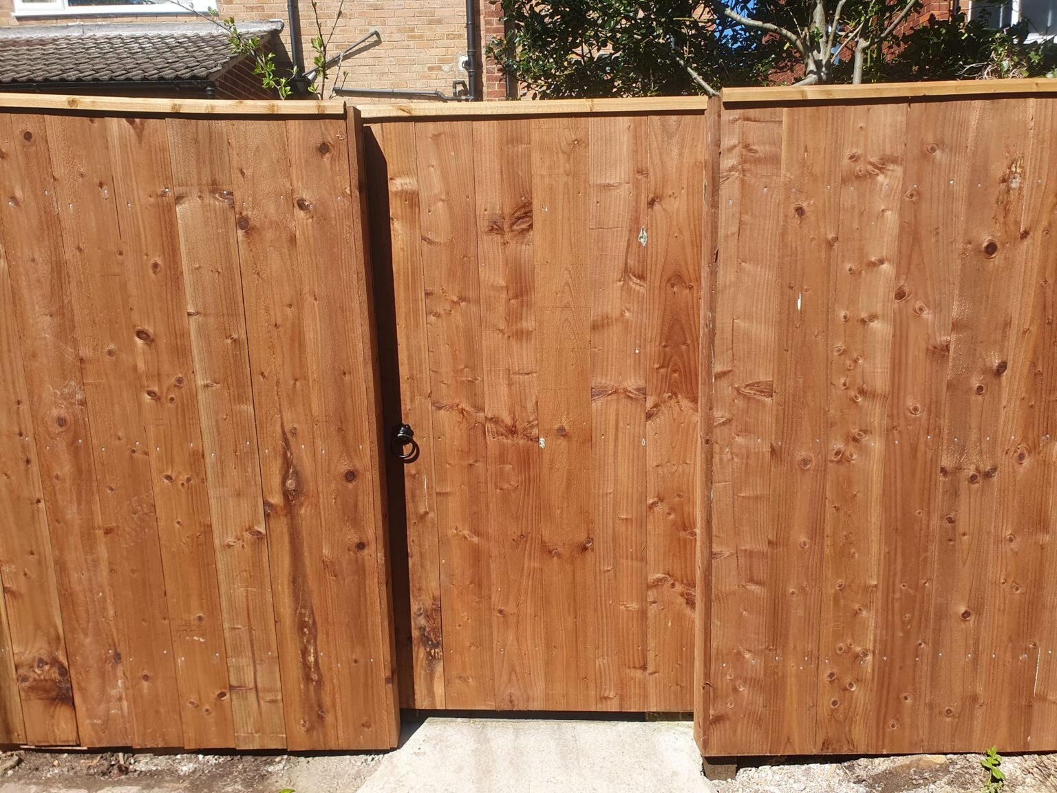 Timber garden fence with a matching wooden gate beside a paved entrance